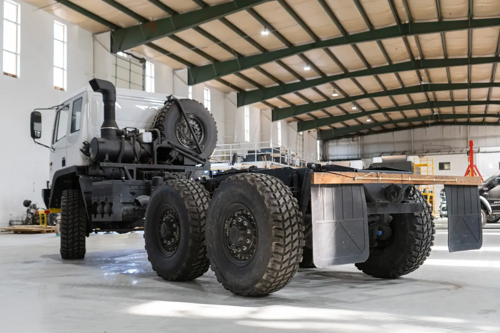 Acela Monterra 6x6 chassis, rear three-quarter view with the spare tire and a frame ready for a body
