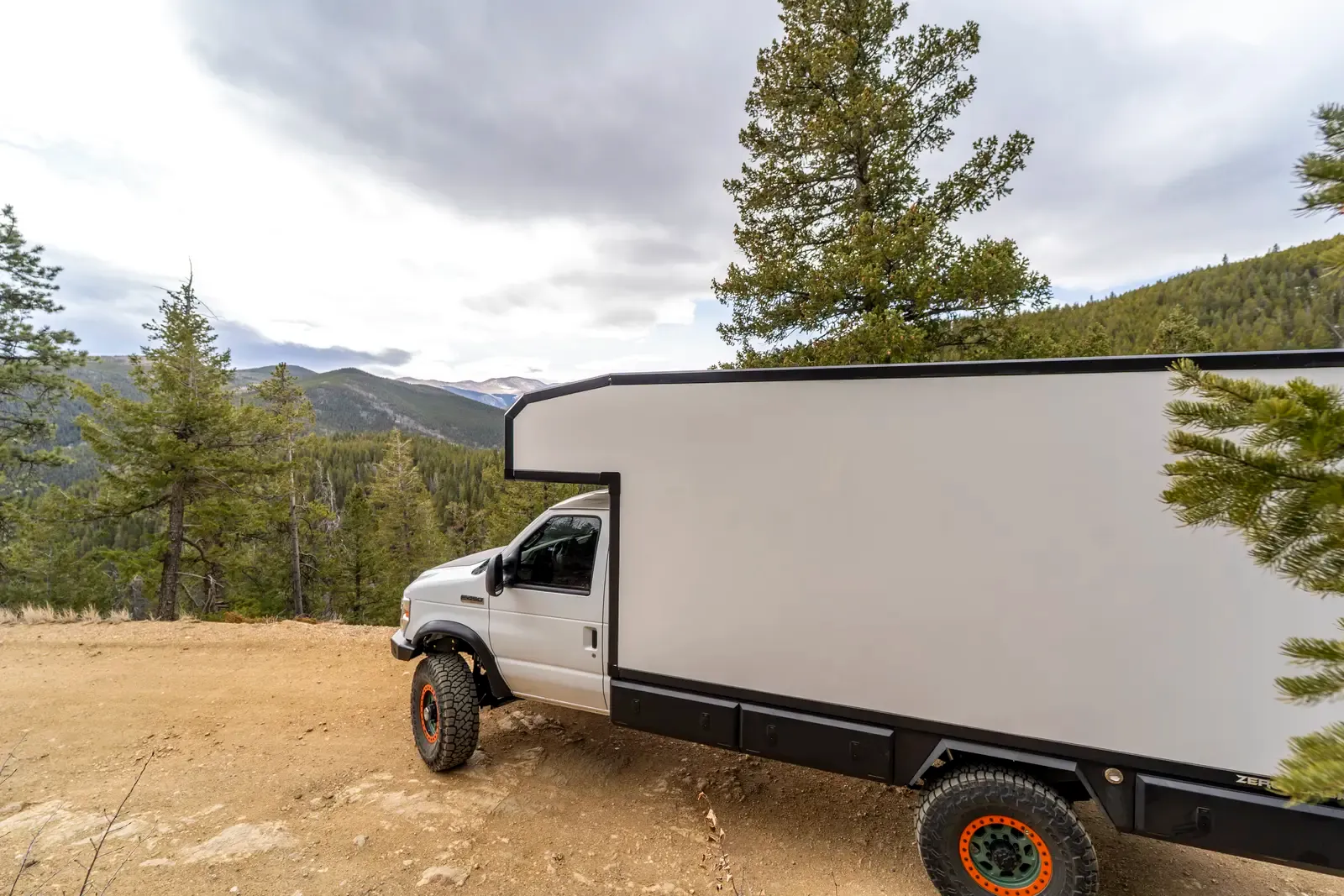White E-158 composite box camper on a Ford E-Series 4x4, side view in a mountain meadow