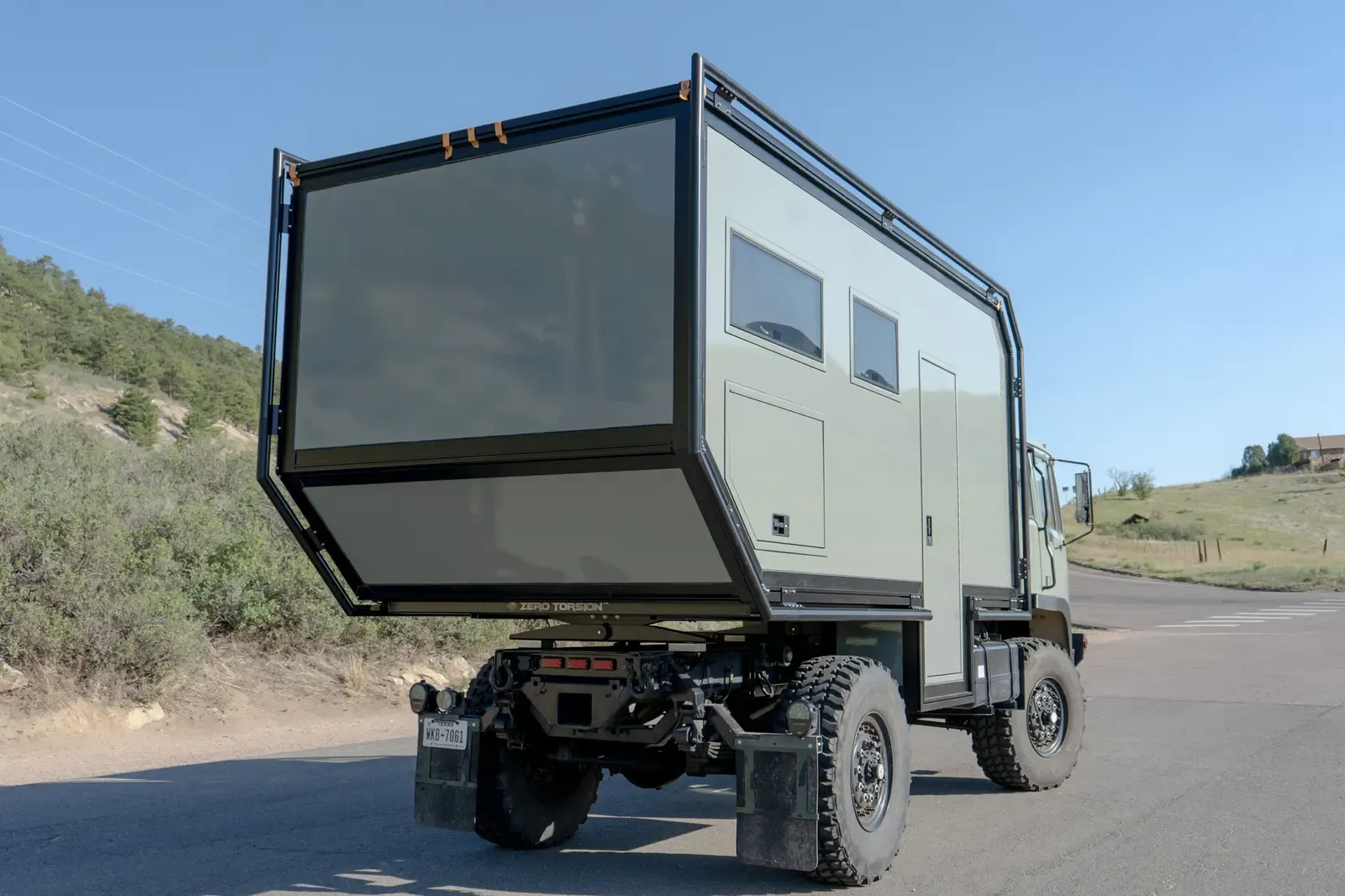 Sage-green LMTV expedition truck, rear three-quarter view showing the composite box body