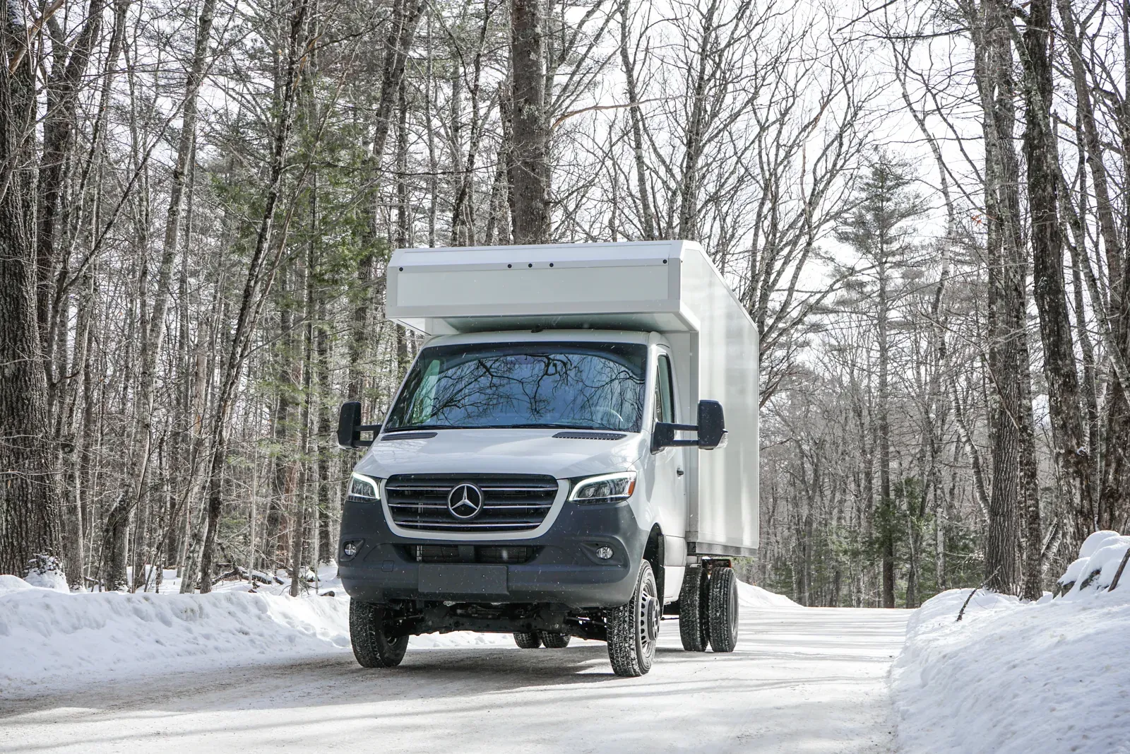 White Mercedes-Benz Sprinter 170 composite body on a snowy forest road in winter
