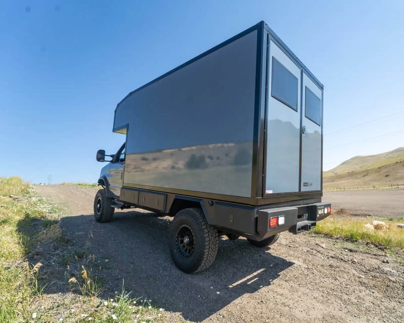 Composite box camper on a Ford E-Series 4x4, rear three-quarter view showing a side window