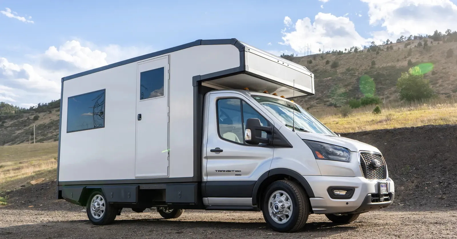 White composite RampDeck body on a Ford Transit 156, front three-quarter view from the passenger side in warm light, rear wall closed