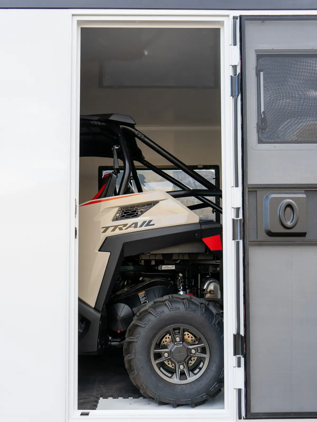 Looking out through the open rear ramp of a Foundation Vehicles RampDeck body toward a side-by-side UTV parked outside