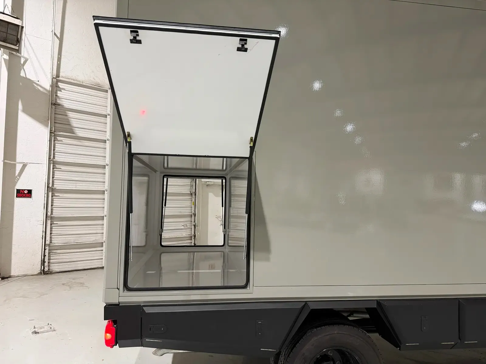 Grey composite box on a Mercedes-Benz Sprinter with the rear doors open, showing the bright interior