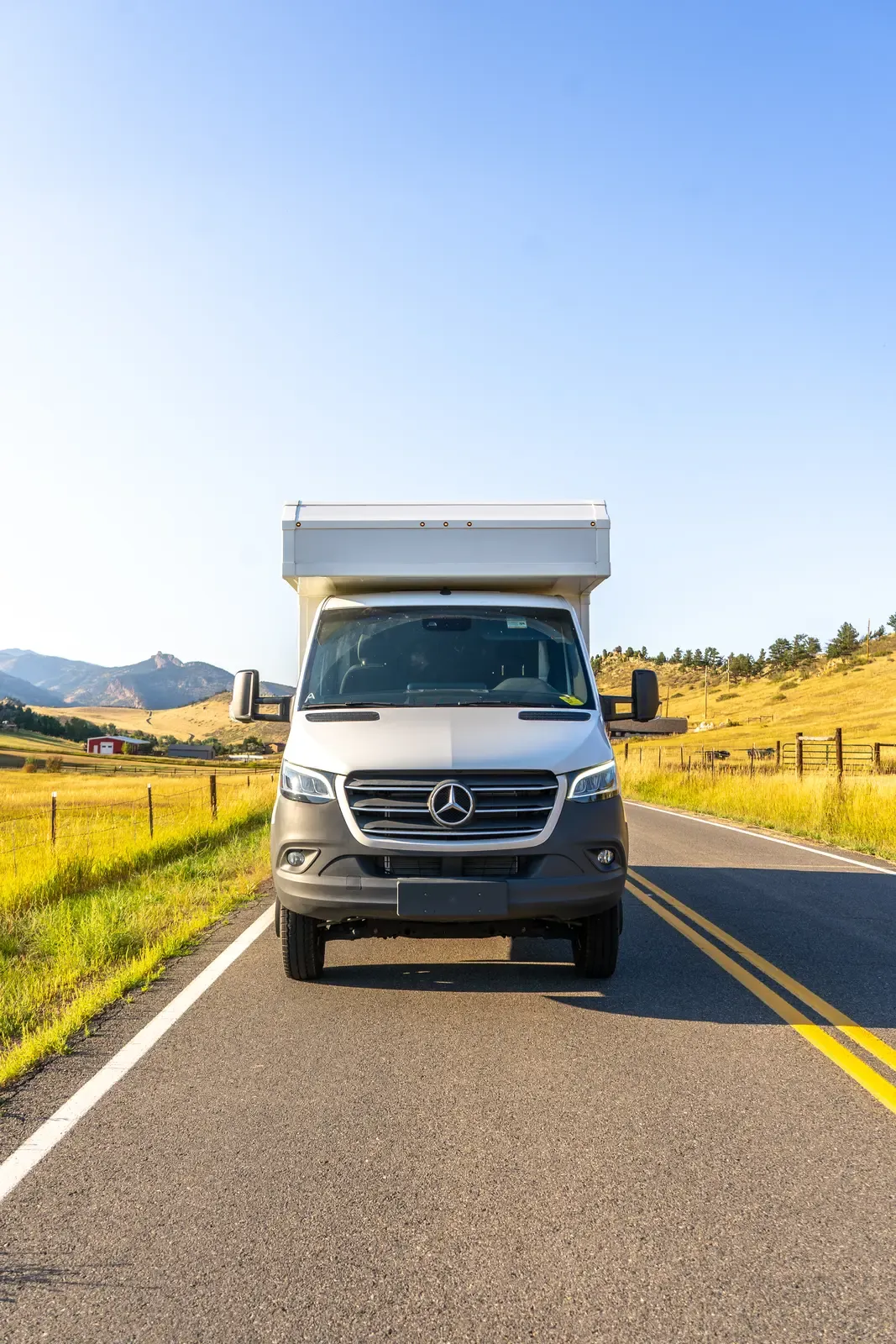 White composite box camper on a Mercedes-Benz Sprinter 170, head-on view on a country road
